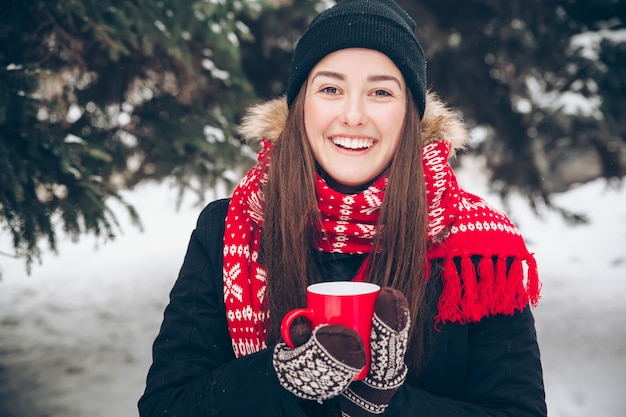 Femme buvant du thé chaud dans la forêt d'hiver