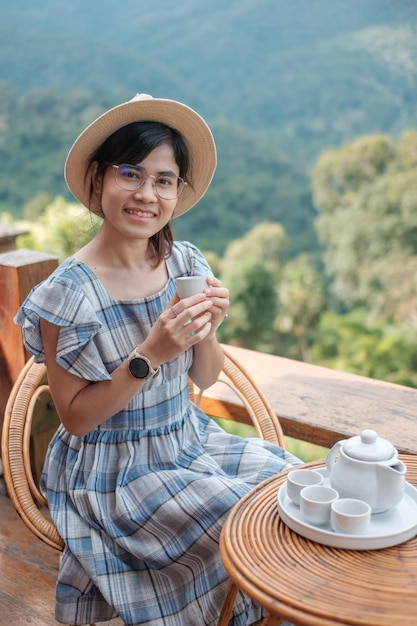 Femme buvant du thé et regardant la vue sur la montagne, jeune blogueur reste à la campagne chez l'habitant le matin. Voyage, vacances, voyage, voyage et concept de détente