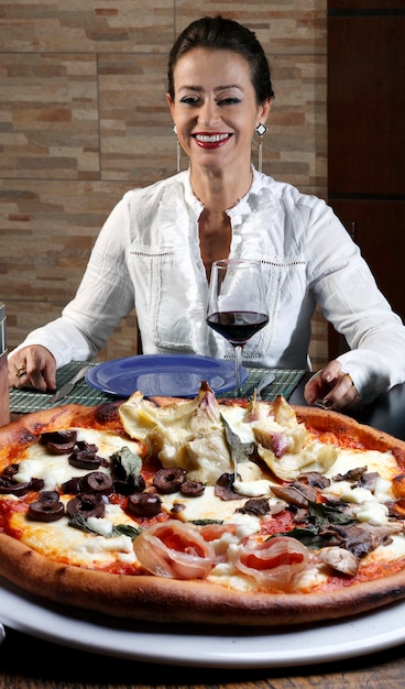 Photo femme buvant du vin rouge et mangeant de la pizza