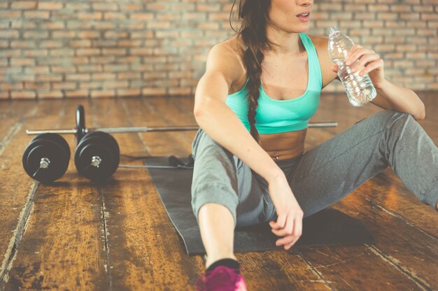 Femme buvant de l'eau après une formation sur le tapis de sport