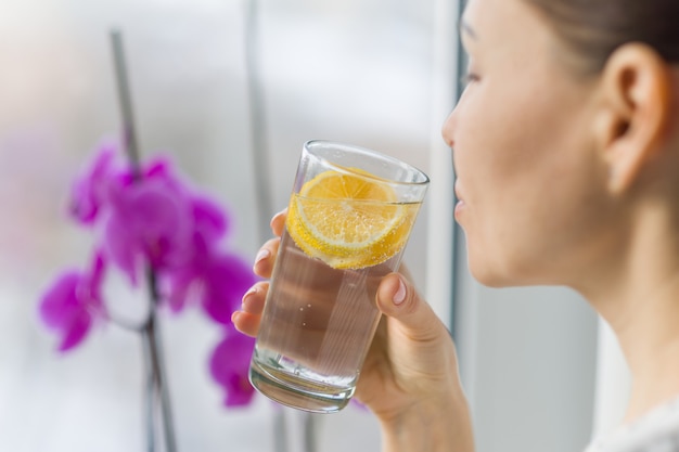 Femme buvant de l&#39;eau avec du citron bio frais