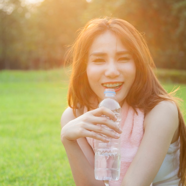 Femme buvant de l&#39;eau et s&#39;asseoir sur l&#39;herbe.