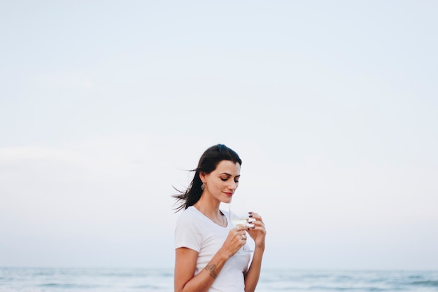 Femme buvant un verre de vin au bord de la plage