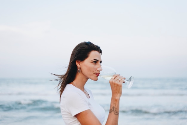 Femme buvant un verre de vin sur la plage