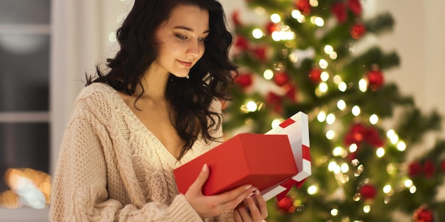 Femme avec cadeau dans la boîte-cadeau près de l'arbre de Noël à la maison