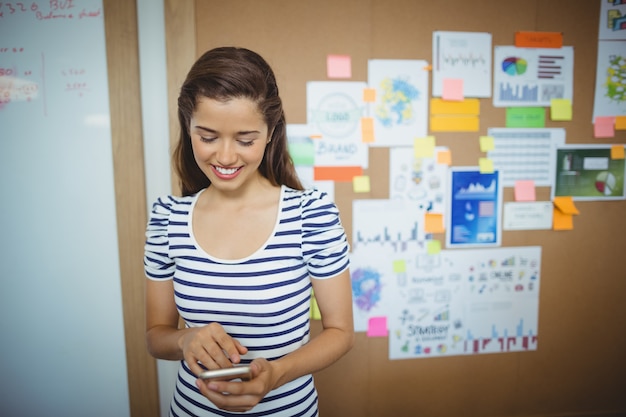 Femme cadre à l'aide de téléphone portable au bureau