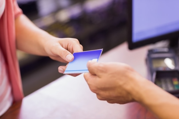 Femme à la caisse enregistreuse payant avec carte de crédit