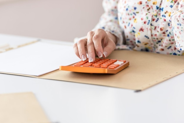 Femme calculant sur la calculatrice de bureau orange