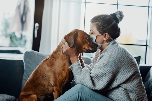 Une femme câline joue avec son chien à la maison à cause de la pandémie du virus corona covid19