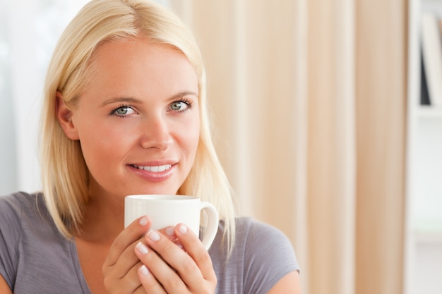 Femme calme assis sur un canapé avec une tasse de thé