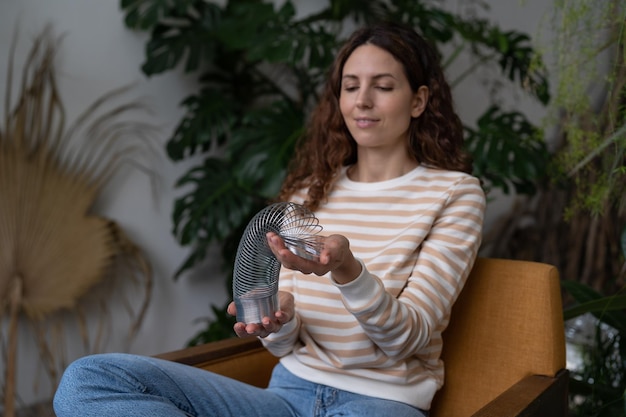 Une femme calme et souriante jouant avec un jouet à ressort pour soulager le stress a une pause du travail au bureau à domicile