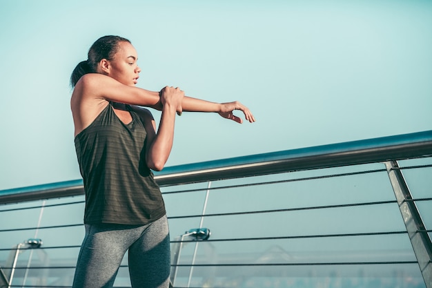 Femme calme touchant son bras droit et regardant loin sur le pont