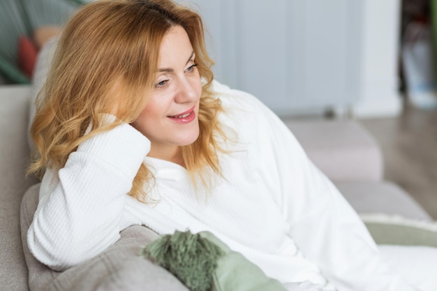 Femme calme avec les yeux fermés reposant sur un canapé confortable, profitant de loisirs paresseux, jolie jeune femme paisible se relaxant, rêvassant