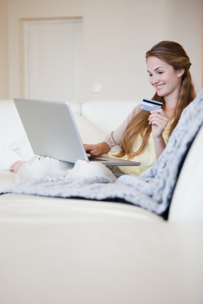 Femme sur le canapé en faisant des achats en ligne