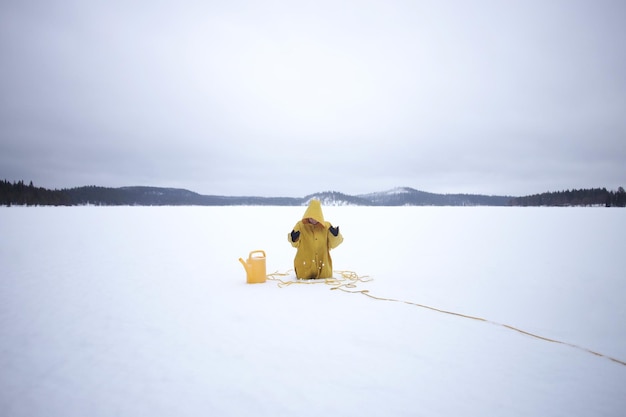 Une femme avec une cape jaune coincée dans la neige.