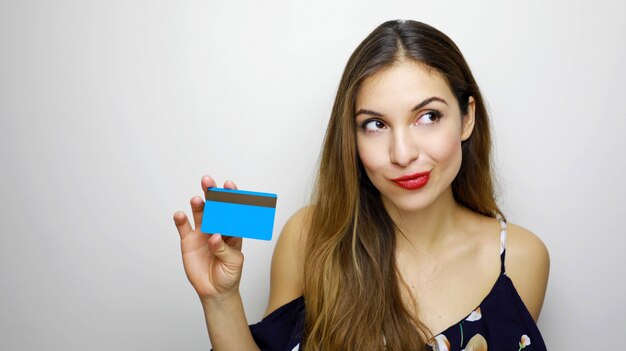 Femme avec carte de crédit en pensant quoi acheter