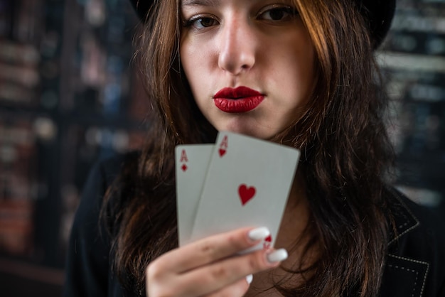 Femme de casino avec des lèvres rouges tenant un as avec des lèvres et des dents séduisantes face en gros plan