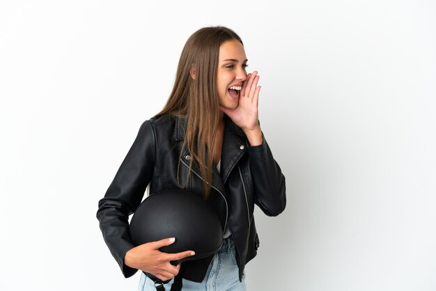 Femme avec un casque de moto sur fond blanc isolé criant avec la bouche grande ouverte sur le côté