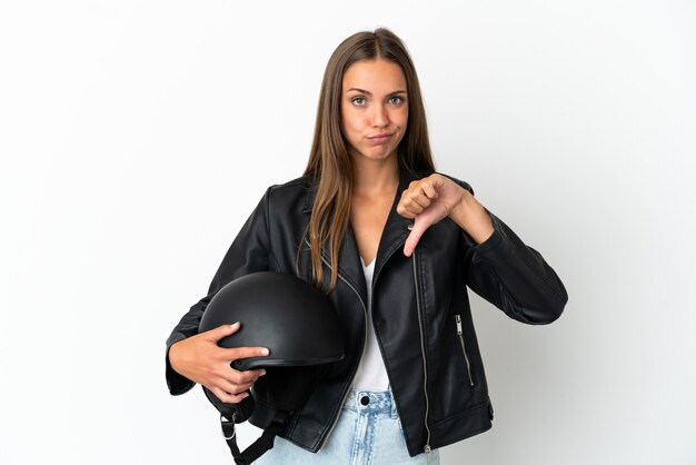 Femme avec un casque de moto sur fond blanc isolé montrant le pouce vers le bas avec une expression négative