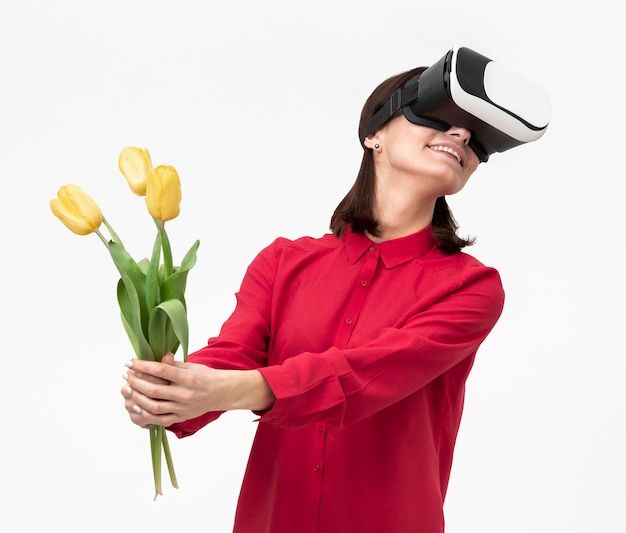 Femme avec casque de réalité virtuelle tenant des fleurs