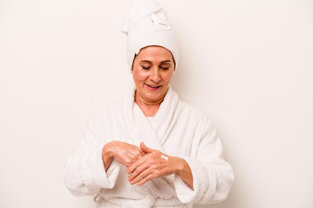 Femme caucasienne d'âge moyen appliquant une crème pour le corps isolée sur fond blanc