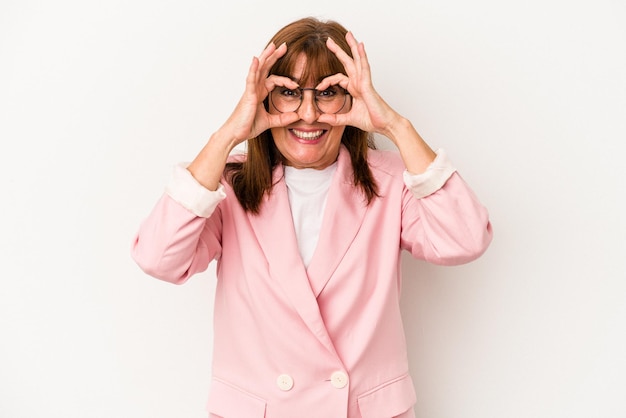 Femme caucasienne d'âge moyen isolée sur fond blanc excité en gardant le geste ok sur les yeux.