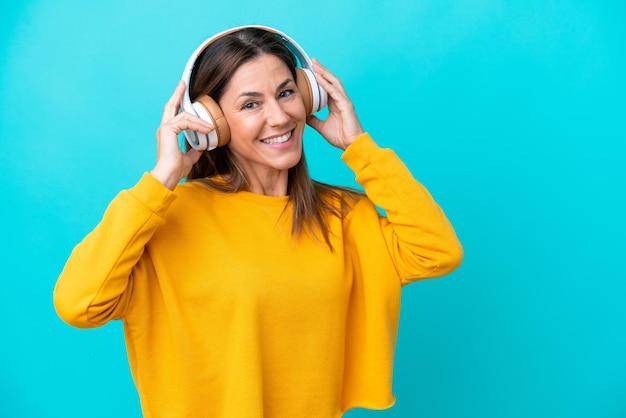 Femme caucasienne d'âge moyen isolée sur fond bleu écoutant de la musique