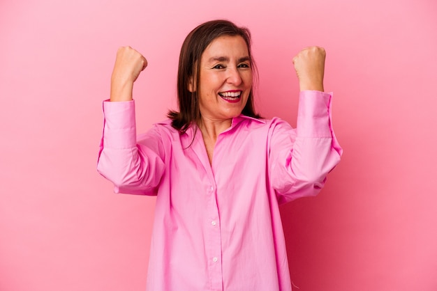 Femme caucasienne d'âge moyen isolée sur fond rose acclamant insouciante et excitée. Notion de victoire.