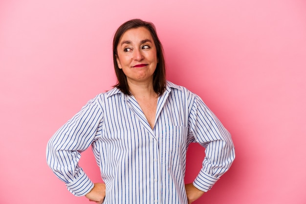 Femme caucasienne d'âge moyen isolée sur fond rose rêvant d'atteindre des objectifs et des buts