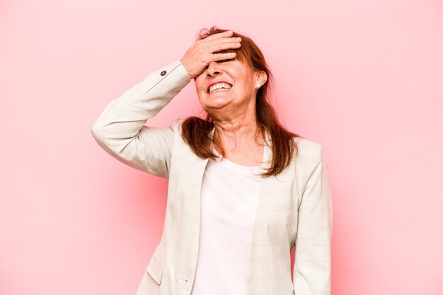 Femme caucasienne d'âge moyen isolée sur fond rose rit joyeusement en gardant les mains sur la tête Concept de bonheur