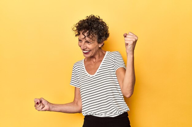 Photo femme caucasienne d'âge moyen sur un jaune vif dansant et s'amusant