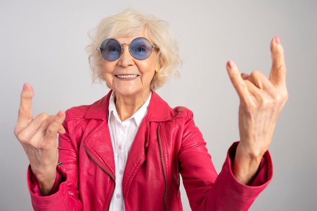 Femme caucasienne âgée heureuse portant des lunettes montrant le geste du rock