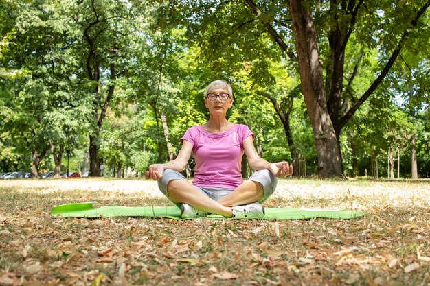 Une femme caucasienne âgée médite et fait du yoga.