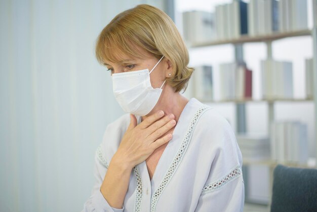 Une femme caucasienne âgée portant un masque se sentant malade