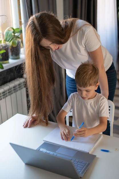 Une femme caucasienne aide son fils à apprendre des leçons Une mère attentionnée vérifie les devoirs de l'enfant Étudier à la maison pendant la quarantaine