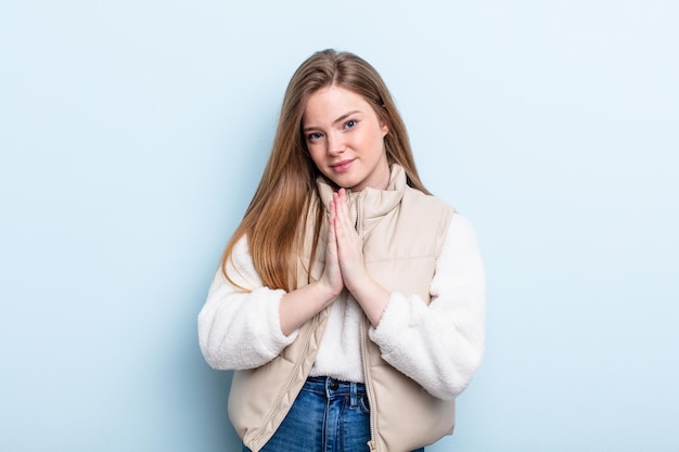 femme caucasienne aux cheveux rouges se sentant inquiète, pleine d'espoir et religieuse, priant fidèlement les paumes pressées, implorant pardon