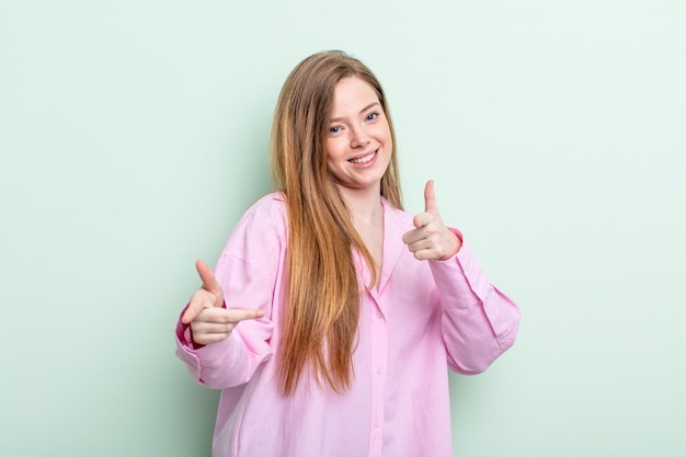 Femme caucasienne aux cheveux roux se sentant heureuse, cool, satisfaite, détendue et réussie, pointant vers la caméra, vous choisissant