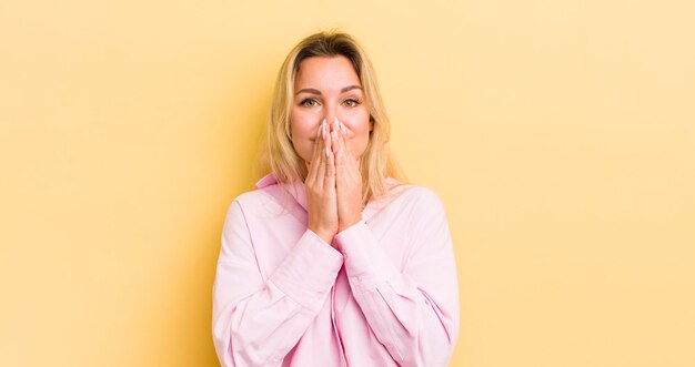 Photo femme caucasienne blonde heureuse et excitée surprise et étonnée couvrant la bouche avec les mains riant avec une expression mignonne