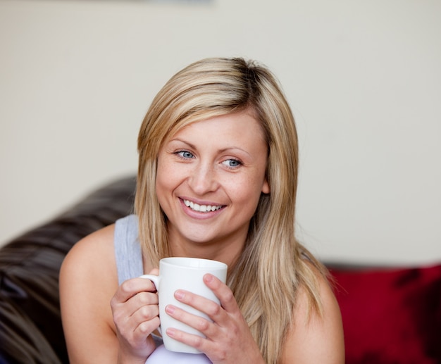 Femme caucasienne, boire une tasse de café sur un canapé