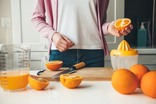 Femme Caucasienne Dans Des Vêtements Décontractés Tranche Des Fruits Et Fait Du Jus à La Maison Dans La Cuisine