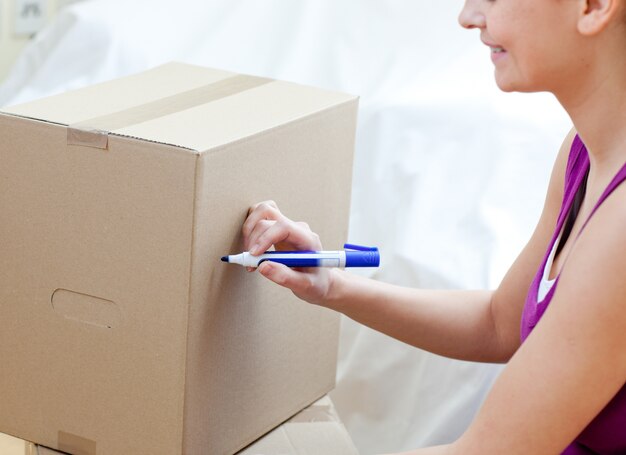 Femme caucasienne écrivant sur une boîte