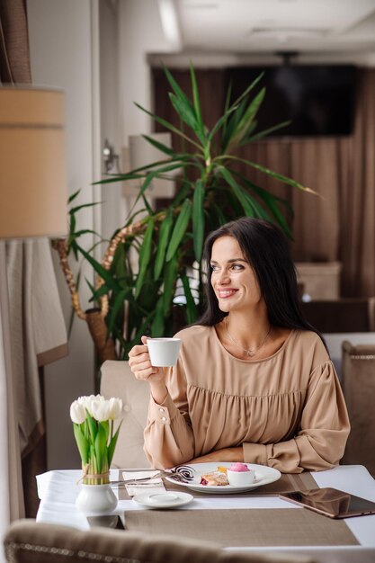 Une femme caucasienne élégante en robe mange un délicieux dessert sucré à la cafétéria