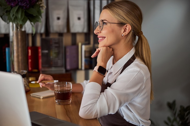 Femme caucasienne élégante tenant la main sous le menton dans le café