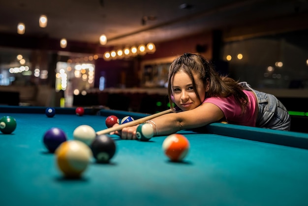 Une femme caucasienne heureuse porte un tissu décontracté en jouant au billard