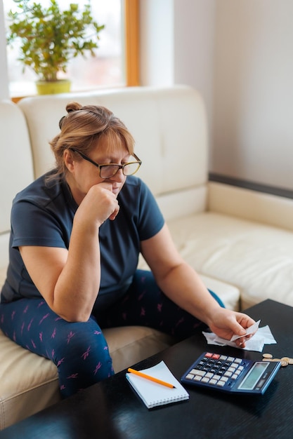 Femme caucasienne inquiète et désespérée calculant les dépenses d'argent domestique faisant de la paperasse et des factures bancaires comptabilisant avec une calculatrice souffrant de stress dans les problèmes financiers et la dépression