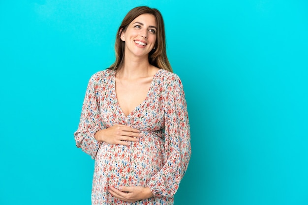 Femme caucasienne isolée sur fond bleu enceinte et heureuse