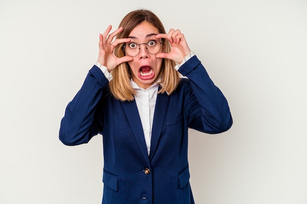 Femme caucasienne jeune entreprise isolée sur un mur blanc en gardant les yeux ouverts pour trouver une opportunité de succès.