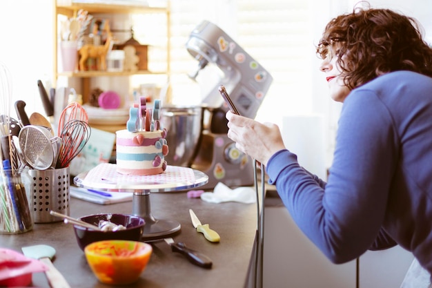 Photo femme caucasienne à la maison prenant une photo d'un gâteau avec son téléphone portable. mise au point sélective.