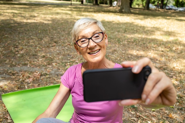 Femme caucasienne senior utilisant un téléphone intelligent et prenant un selfie après l'entraînement.