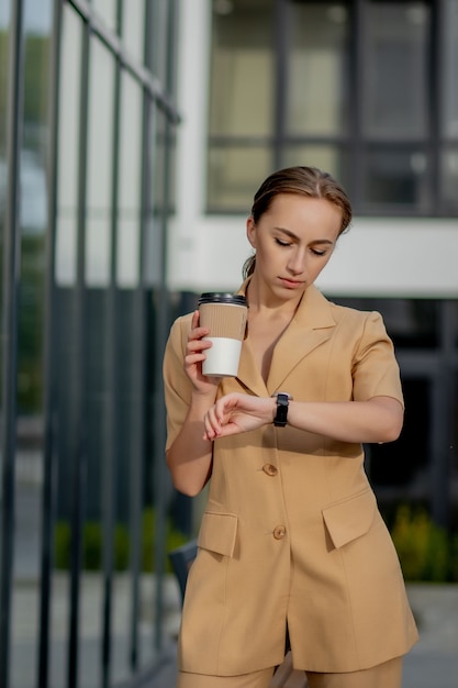 Femme caucasienne avec smartphone debout contre le bâtiment de la rue.